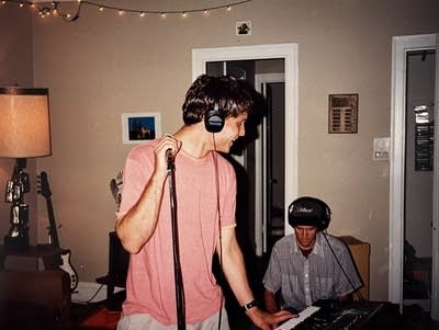 Two men play music in an apartment living room.