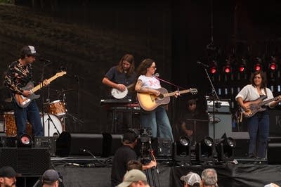 Waxahatchee's Katie Crutchfield sings into a microphone and strums a guitar.