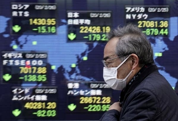 A pedestrian walks past a display showing information of global stock markets outside a securities office in Tokyo, Japan, 26 February 2020.