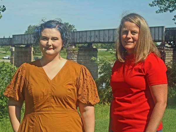 two women stand on a river bank