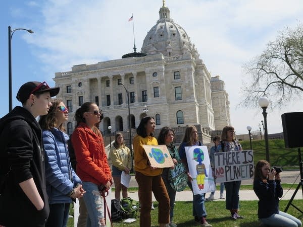 Teens attending the Youth Climate Strike rally hold signs.