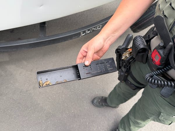 A person holds a container with zebra mussels inside.