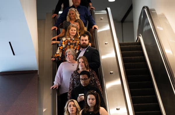 A group of people rides an escalator down.