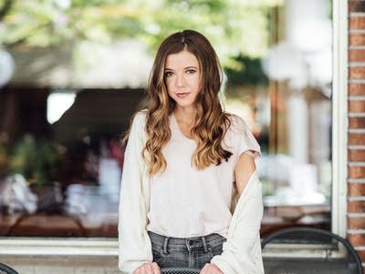 A woman stands on the patio of a restaurant in summer