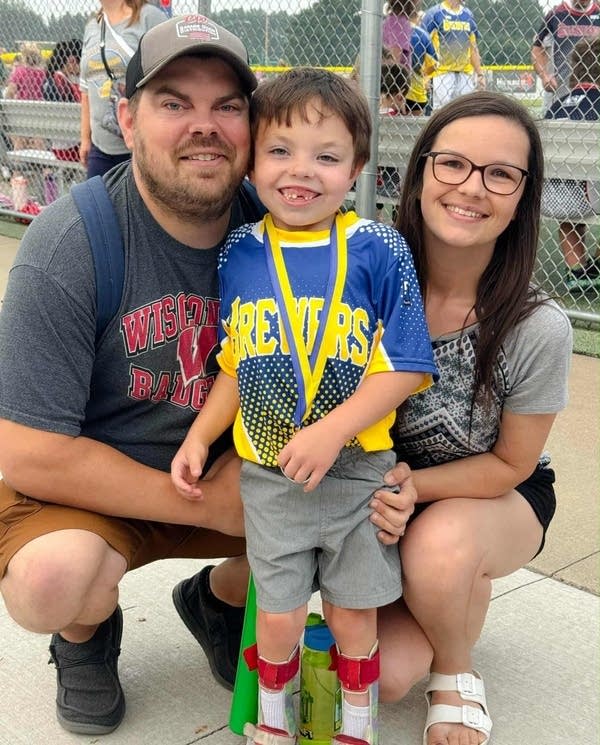 A mother and father pose for a photo with their young son.