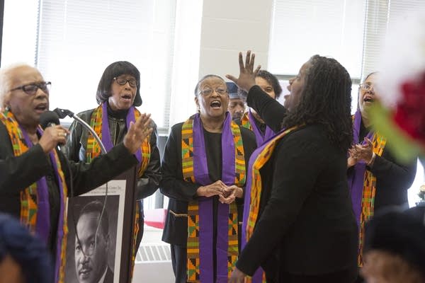 three people sing wearing matching robes