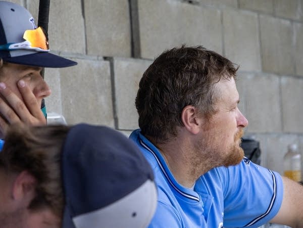 a man sits in front of a brick wall 