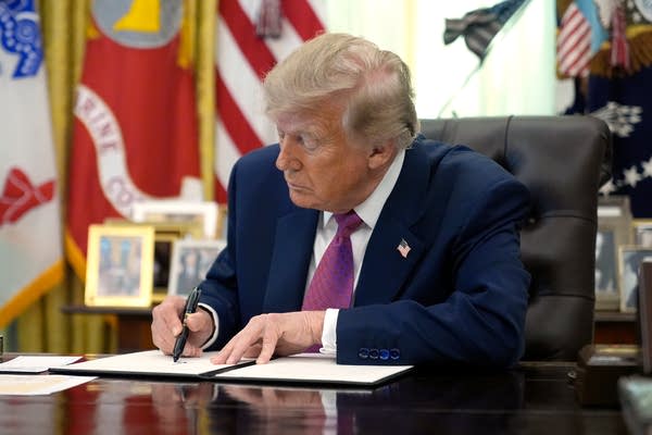 President Donald Trump signs a document.