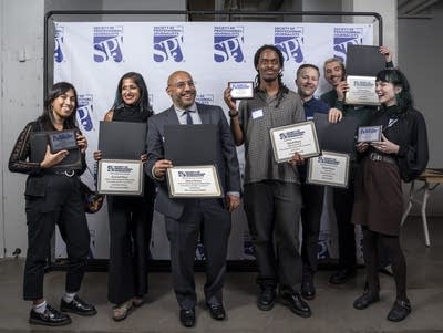 Seven people hold awards in front of an SPJ backdrop.