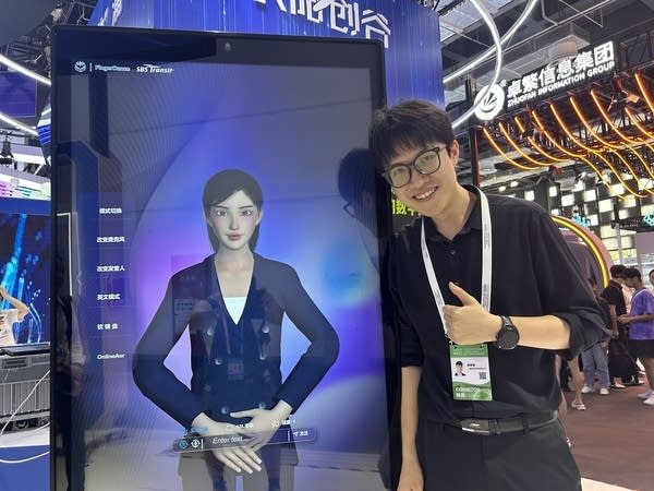Cheng Sirui of Finger Dance leaning next to his AI avatar that can translate languages into sign languages at the World AI conference in Shanghai