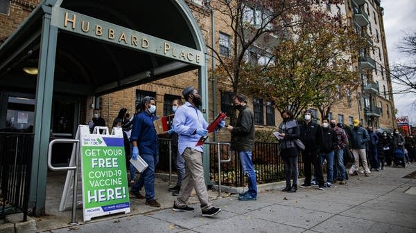 WASHINGTON, DC - DECEMBER 03: People line up outside of a free COVID-19 vaccination site that opened today in the Hubbard Place apartment building on December 3, 2021 in Washington, DC. The DC Department of Health is stepping up vaccination and booster shots as more cases of the Omicron variant are being discovered in the United States. (Photo by Samuel Corum/Getty Images)