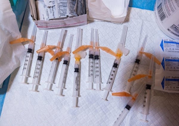 Syringes filled with vaccines lay on a table. 