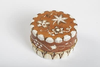 An orange-brown and white handmade basket with varying star patterns.