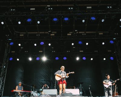 Jensen McRae performing on stage with an acoustic guitar