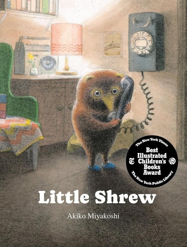 Cover for a book called "Little Shrew." It's an image of a shrew standing upright in a living room and holding a phone up to its ear.