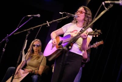 One musician plays cajon while another sings and plays guitar