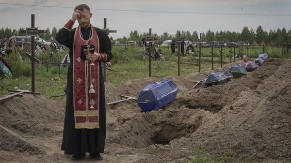 A priest prays for unidentified civilians