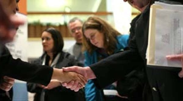A job seeker shakes hands with a potential employer at a job fair in San Francisco