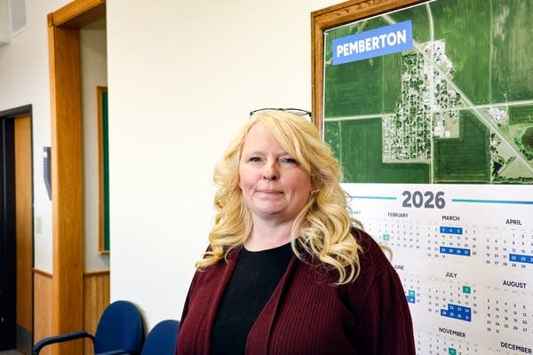 A woman poses for a photo inside an office, next to a map of Pemberton.