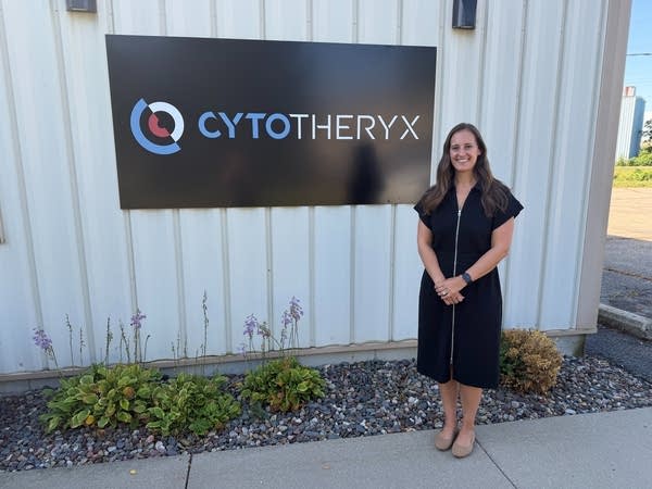 A woman posing by Cytotheryx sign.