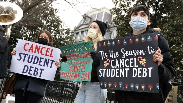 Activists hold festive signs calling on President Joe Biden to cancel student debt. 