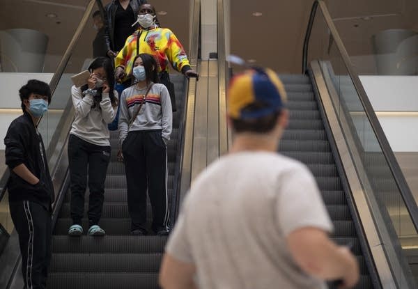 People wear masks on an escalator.