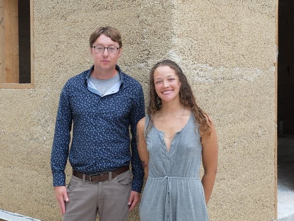 a man and a woman stand in front of a partially constructed building