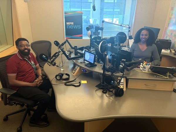 two people smiling in a broadcast studio