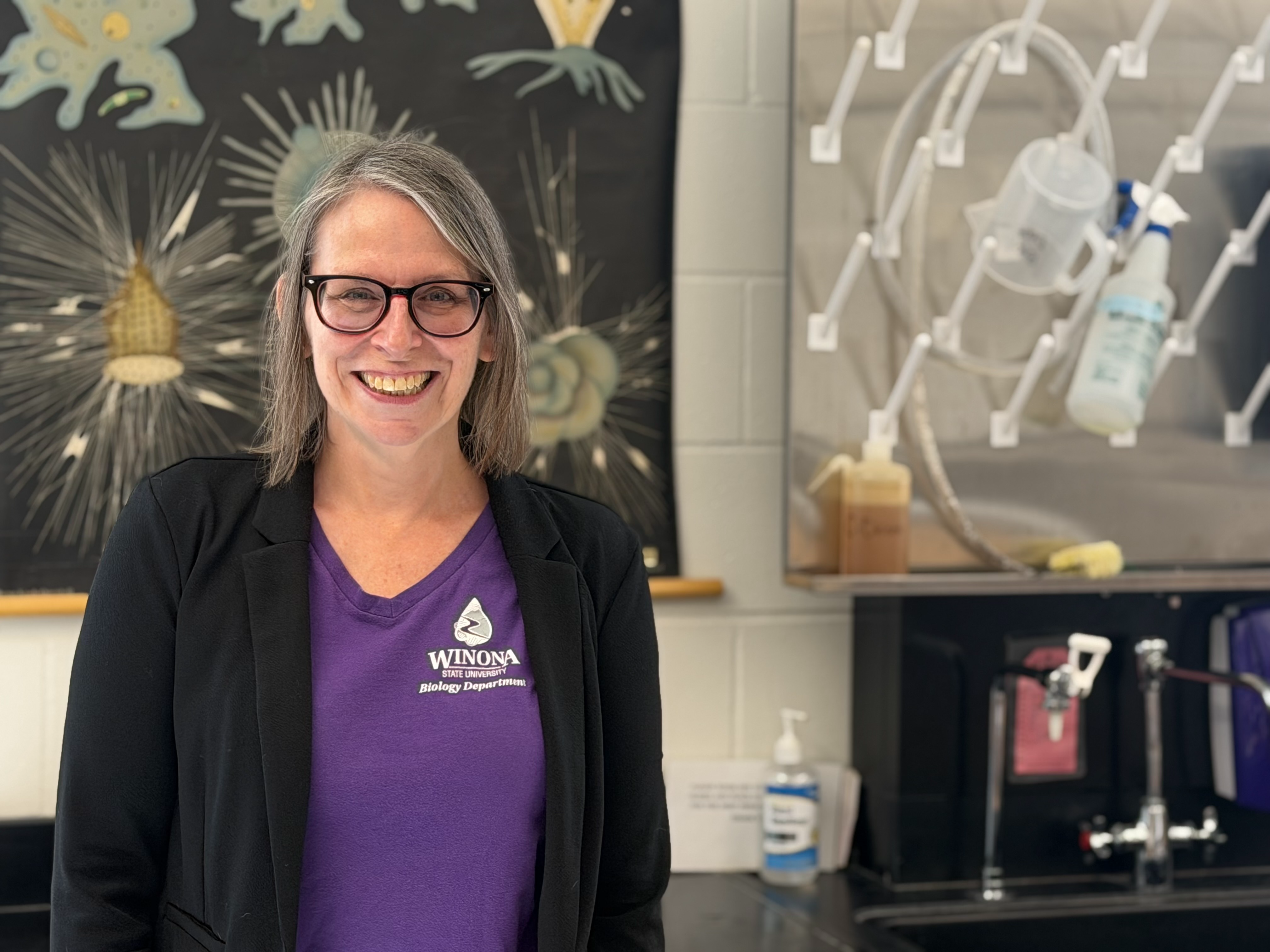 A woman in black and purple shirt smiles for photo