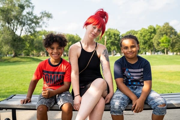 A woman sits with her two sons.