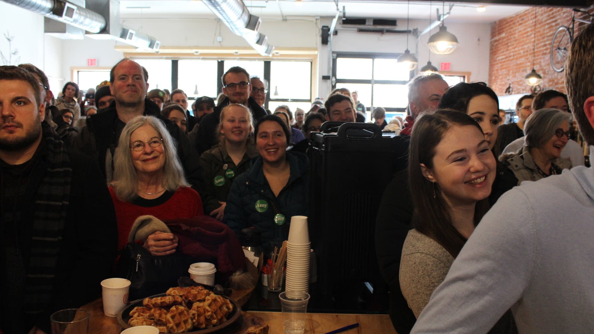 A crowd listens to Amy Klobuchar speak at a presidential campaign stop