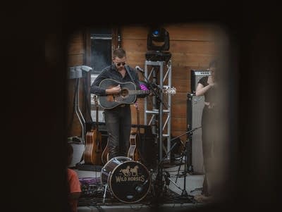 A man strums a guitar on an outdoor stage.