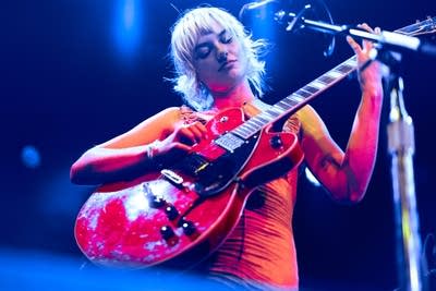 A musician plays guitar onstage in a music venue