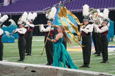 A marching band performs on the field of a football stadium.