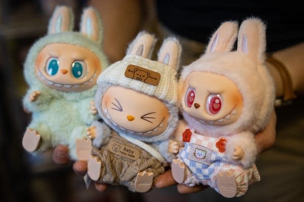 A person holds up three dolls