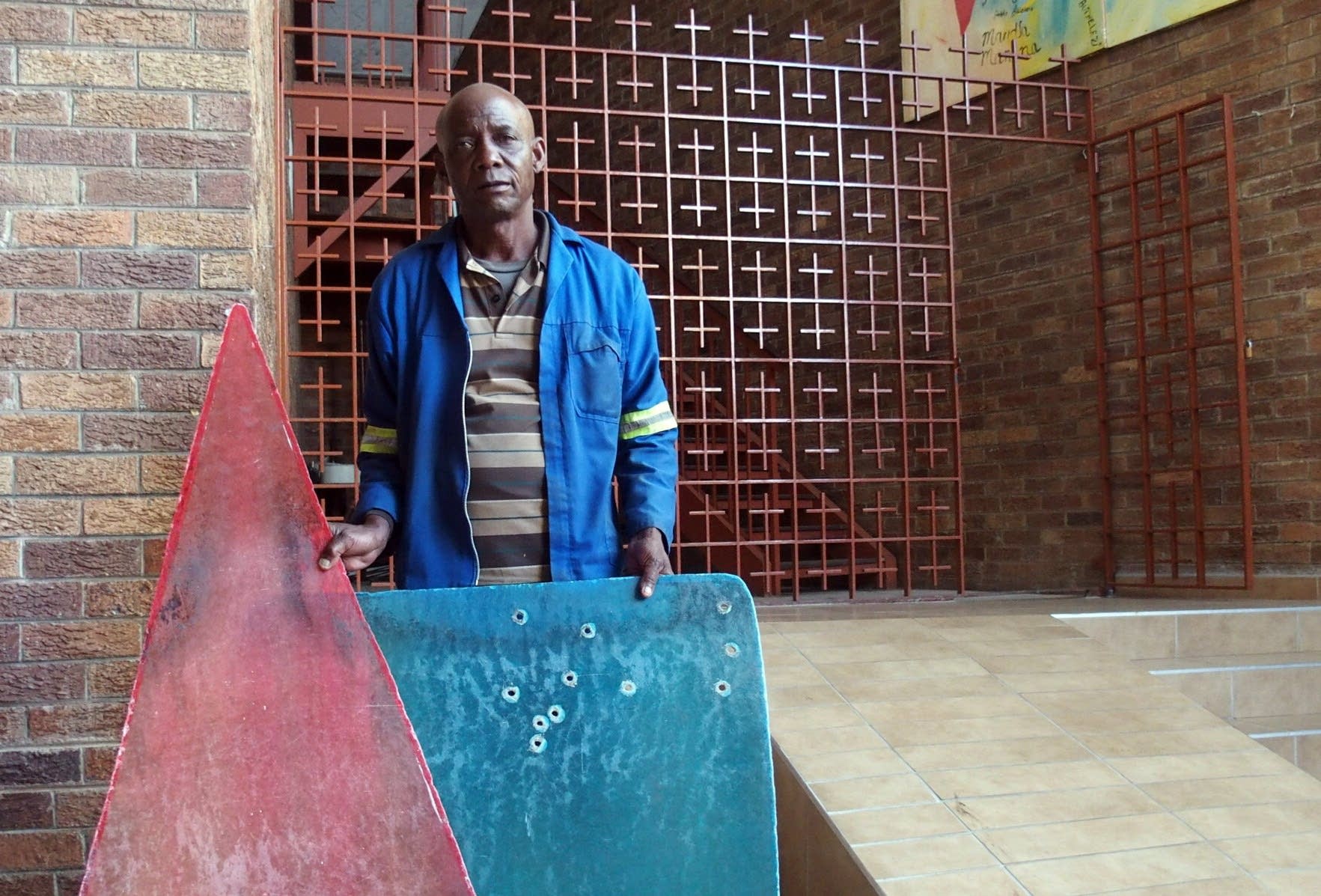 Regina Mundi caretaker Danny Dube holds bullet-riddled fiberglass panels.