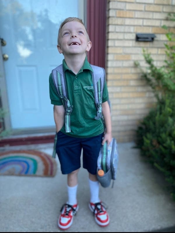 A child looks upwards and wears a school uniform