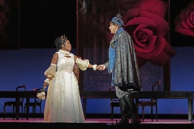 Two performers interact onstage during an operatic production