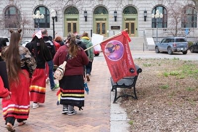 Demonstrators marching outside one of them holding a flag