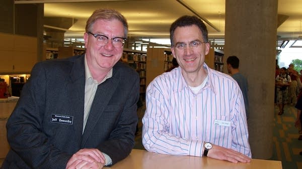 Poster Two men smiling by a bookshelf in a library