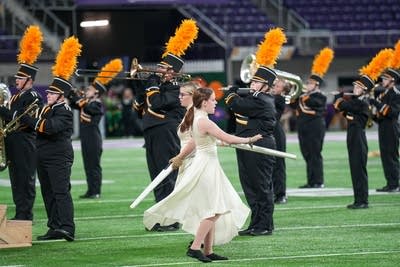 A marching band performs on the field of a football stadium.