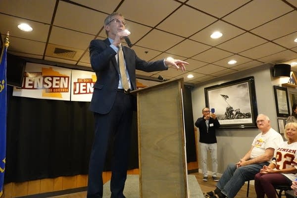 A man speaks into a microphone as he stands at a podium