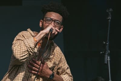 A musician raps into a microphone onstage