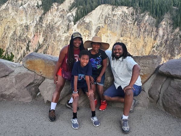 Black family of four poses for photo in front of large canyon