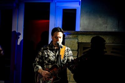 A musician sings and plays dobro onstage