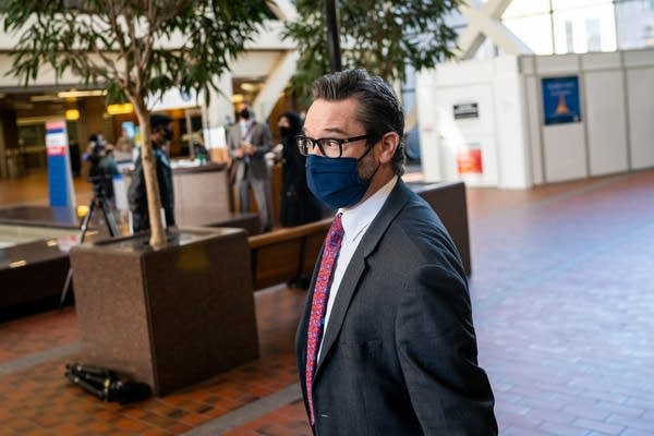 A man with a navy blue mask stands in a lobby.