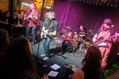 Four musicians performing onstage