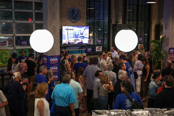 A crowd of people fills a brewery for an election watch party.