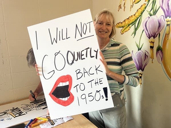 woman holds up sign