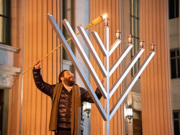 Rabbi Yitzi Steiner lights the menorah at Northrup Plaza during a Hanukkah celebration put on by Minnesota Hillel and Chabad of the University of Minnesota for the fourth day of Hanukkah on Sunday, Dec. 10, 2023.